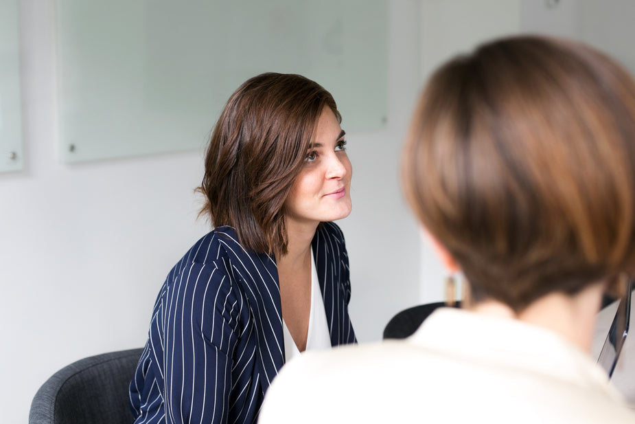 Business Frauen sitzen am Tisch und eine schaut interessiert 